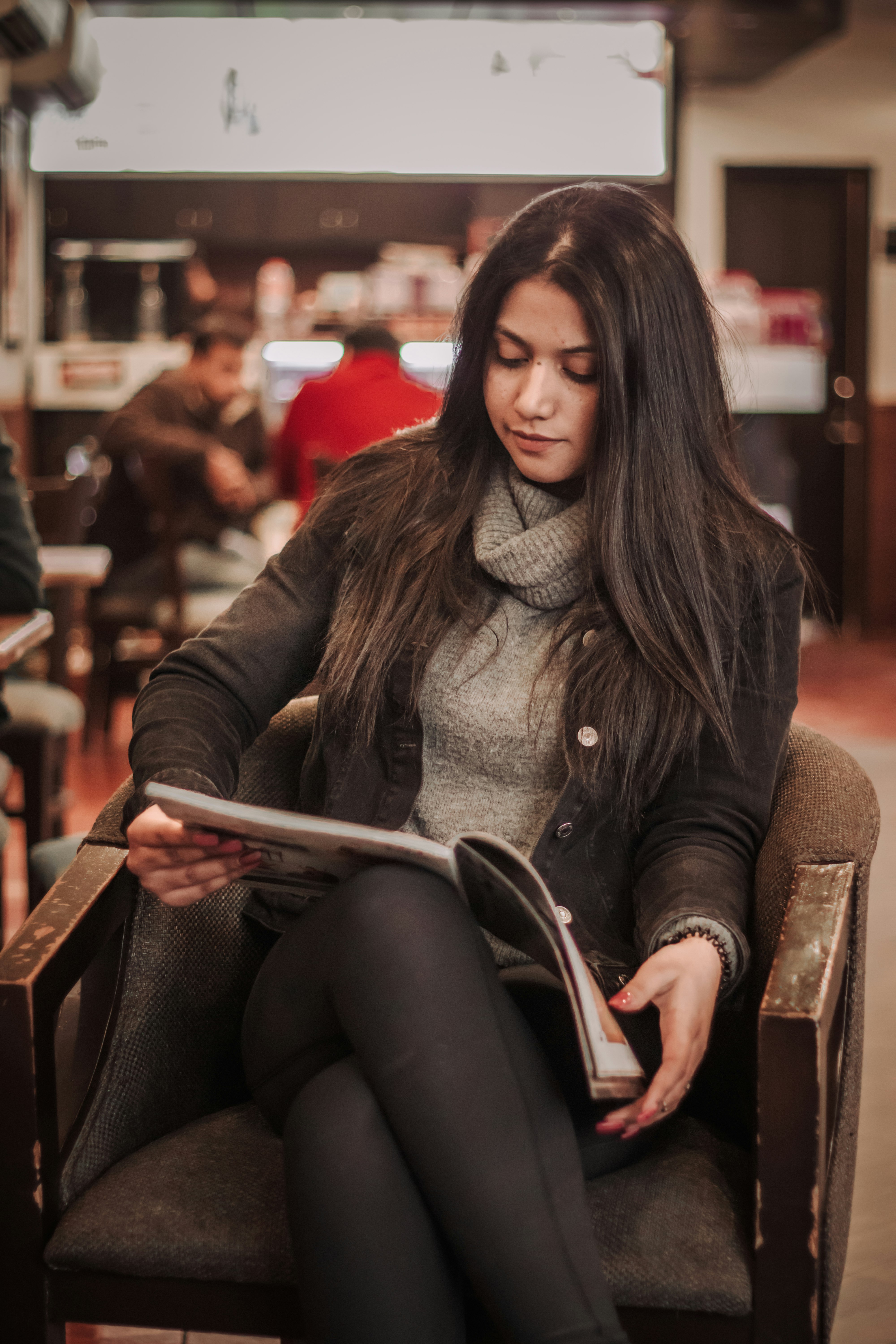 woman in gray scarf and black coat sitting on brown wooden chair